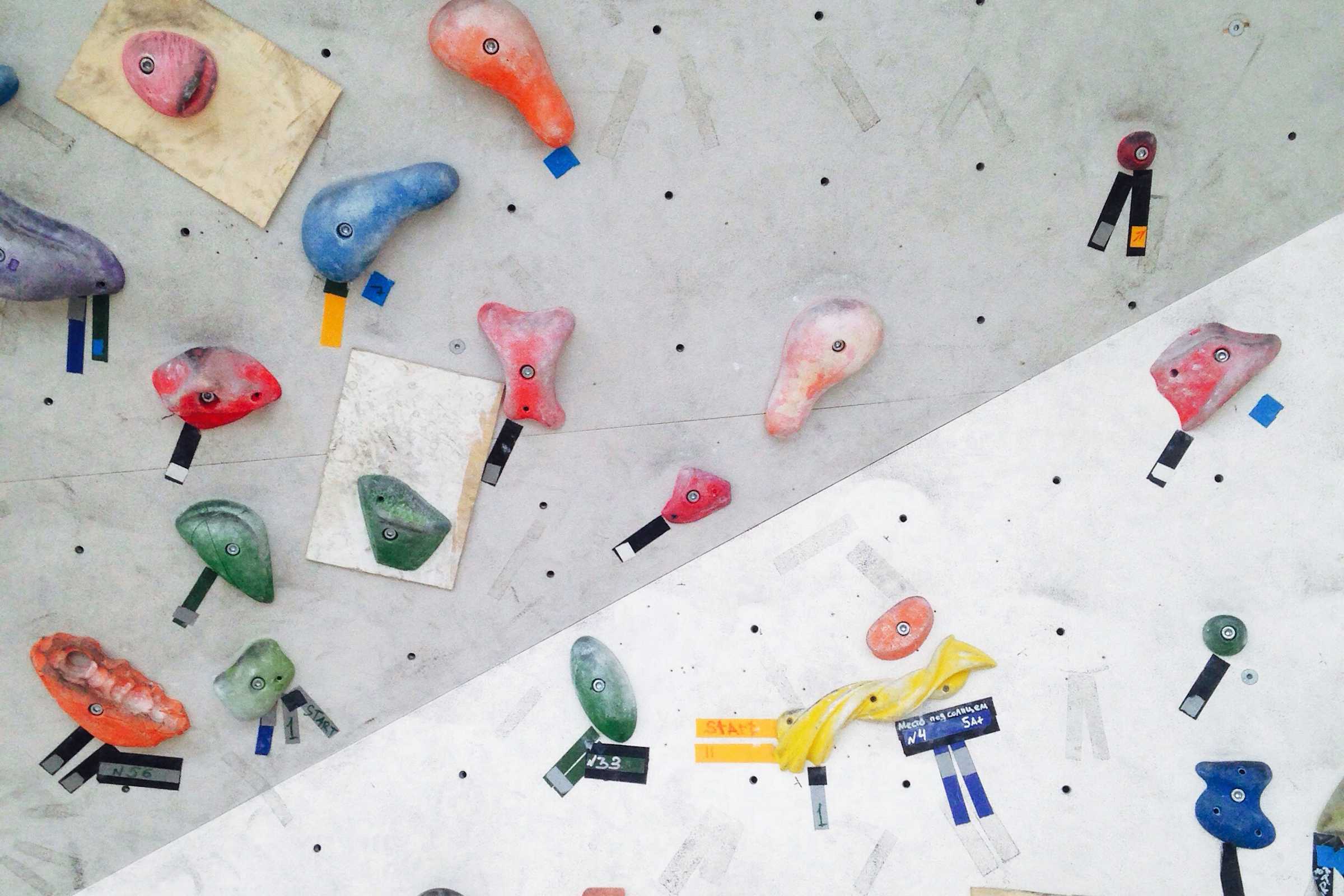 Überhängendes Boulder-Wandsegment mit bunten Griffen, von unten gegen die Hallendecke fotografiert